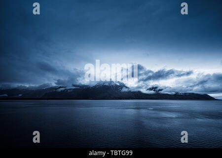 Am frühen Morgen Wolken bilden über die schneebedeckten Berge hinter den Genfer See mit Lausanne im Vordergrund. Stockfoto