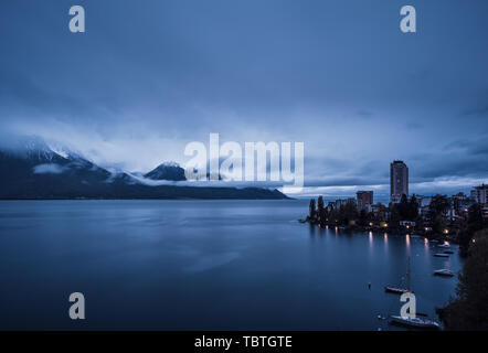 Am frühen Morgen Wolken bilden über die schneebedeckten Berge hinter den Genfer See mit Lausanne im Vordergrund. Stockfoto