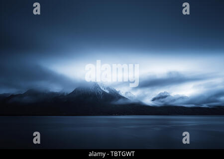 Am frühen Morgen Wolken bilden über die schneebedeckten Berge hinter den Genfer See mit Lausanne im Vordergrund. Stockfoto