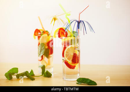 Erfrischend lebendige Sommer Getränke mit Zitrone, Erdbeere und Minze und bunte Strohhalme auf dem hölzernen Tisch Stockfoto
