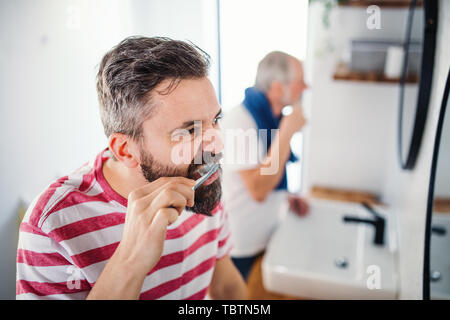 Ein erwachsener hipster Sohn und Vater die Zähne putzen Zuhause zu Hause. Stockfoto