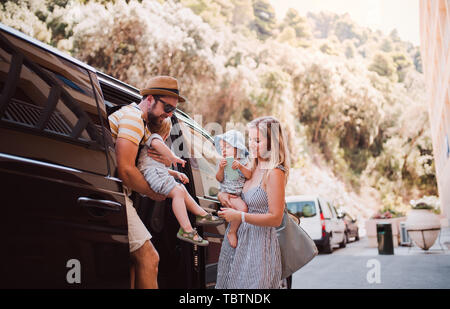 Eine junge Familie mit 2 Kleinkind Kinder aus dem Taxi auf Sommerurlaub. Stockfoto