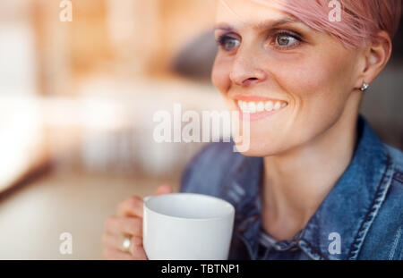 Eine Nahaufnahme Porträt der jungen attraktiven Frau, die durch die Fenster zu Hause. Stockfoto