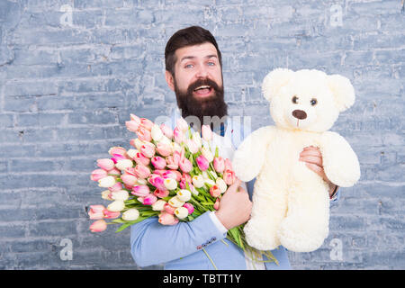 Warten auf Darling. Mann gut gepflegt Verschleiß tuxedo Bow Tie halten Blumen Tulpen Bouquet und großen Teddybären Spielzeug. Laden Sie dating. Romantisches Geschenk. Romantischen Mann. Macho fertig, romantisches Date. Stockfoto