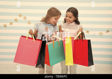 Einkaufen mit beste Freundin Konzept. Mädchen wie einkaufen. Die Kinder glücklich kleine Mädchen halten Einkaufstaschen. Viel Spaß beim Shoppen mit der besten Freundin oder Schwester. Mädchenhafte Glück. Die Kinder glücklich tragen Bündel Pakete. Stockfoto