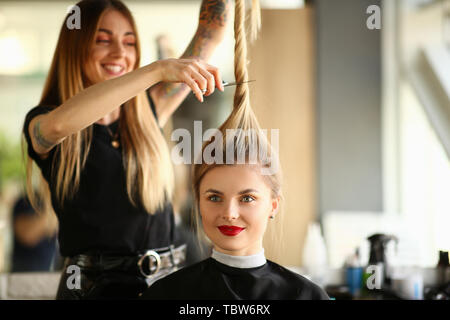Friseur Schneiden mit Schere Pferdeschwanz Portrait. Frau mit Lächeln, Haarschnitt im Beauty Salon. Frau mit langen, geraden Haare Sitzen im Studio Stockfoto