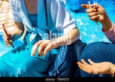 Artist Anwendung Henna Tattoo auf Frauen Hände in den Straßen von Marrakesch, Marokko, Afrika Stockfoto