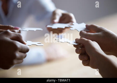 Schließen sich Mitglieder der multirassischen Team holding Stücke von Puzzle Stockfoto