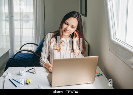 Mädchen in Kopfhörer arbeitet am Laptop im Home Office und hört Musik oder einen Podcast. Stockfoto