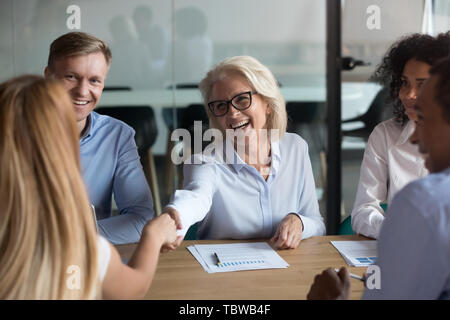 Reife Geschäftsfrau zitternden Hand der Business Partner bei der Sitzung Stockfoto