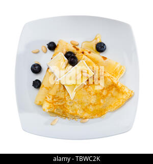 Blick von oben auf die zarte Crepes serviert mit Schichten aus weichem Brie, Honig, Pinienkernen und frischem Blueberry. Auf weissem Hintergrund Stockfoto