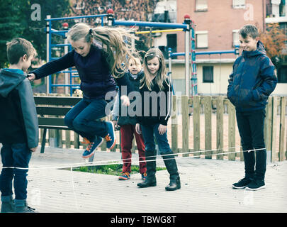 Positive russische Kinder Überspringen auf chinesische Springen elastische Kordel im Hof Stockfoto