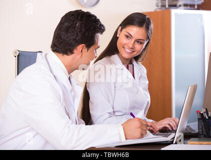 Junge lächelnde intern fragen Beratung von medizinischen Betreuer an der Klinik Rezeption Stockfoto
