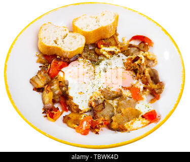 Leckere Spiegeleier mit Speck und Tomaten serviert mit frischem Baguette. Auf weissem Hintergrund Stockfoto