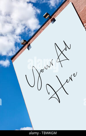 Riesige leere Anschlagtafel auf einen roten Backsteinbau gegen den blauen Himmel mit Wolken an einem sonnigen Tag Stockfoto