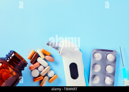 Pharmazeutische medizinische Pillen und Kapseln in Packungen, einem Injektor Spritze, Ohr Thermometer und Tabletten aus einer Droge Flasche verschüttet Stockfoto