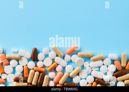 Haufen von bunten Pillen, Tabletten und Kapseln auf blauem Hintergrund mit Kopie Platz für Text. Von oben nach unten anzeigen. Stockfoto