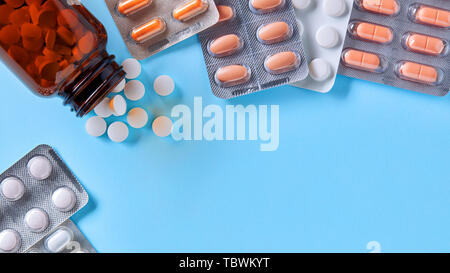 Pharmazeutische medizinische Pillen und Kapseln in Packs und Tabletten aus einer Droge Flasche auf blauem Hintergrund mit Kopie Raum verschüttet Stockfoto