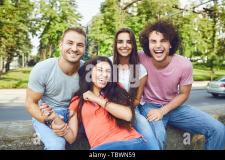 Eine Gruppe von Freunden Lachen sitzen in einem Sommer Park. Stockfoto