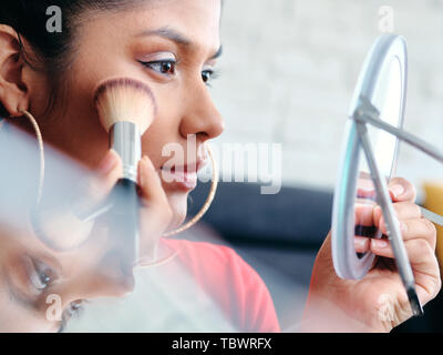 In der Nähe der weiblichen Experimentieren mit Make-up Techniken mit Blusher, Bürste und Stiftung. Stockfoto