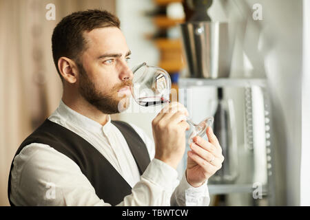Kopf und Schultern Portrait von professionellen Sommelier holding Glas Wein während der Weinprobe, kopieren Raum Stockfoto