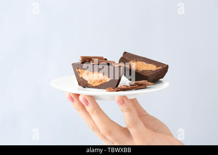 Weibliche hand mit Schokolade butter Cups auf hellen Hintergrund Stockfoto