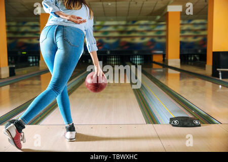 Junge Frau spielen Bowling im Club Stockfoto