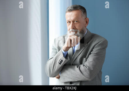 Portrait von Stattlichen älterer Mann in der Nähe der Fenster zu Hause Stockfoto