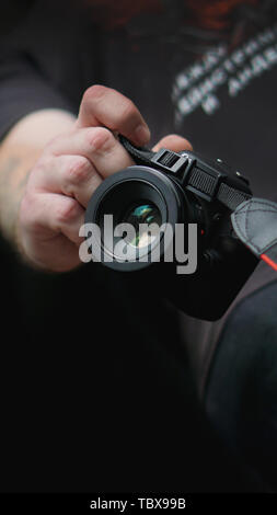 Junger Mann Fotograf hält Kamera. Fotograf Konzept. Stockfoto