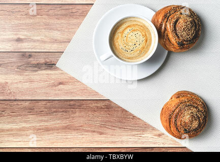 Perfektes Frühstück mit hausgemachten Zimt Brötchen und Kaffee auf Holztisch. Im rustikalen Stil. Ansicht von oben. Stockfoto