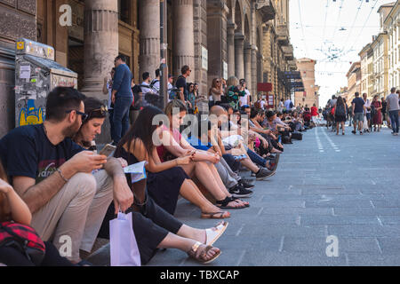 Menschen am Rande der Straße im Zentrum von Bologna, Italien. Jedes Wochenende im Zentrum der Stadt ist der Verkehr gestoppt. Stockfoto