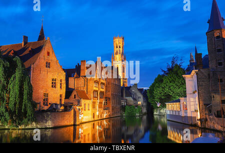 Berühmte Ansicht von Brügge touristische Sehenswürdigkeiten Attraktion - rozenhoedkaai Kanal mit Glockenturm und alte Häuser am Kanal mit Baum in der Nacht. Belgien Stockfoto