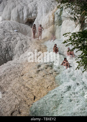 Bagni San Filippo, Italien - 24 April 2019: Menschen Ruhe auf den thermischen Salz Wasserfälle der Mineralquellen von Bagni San Filippo an einem sonnigen Tag. Stockfoto