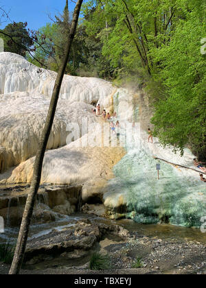 Bagni San Filippo, Italien - 24 April 2019: Menschen Ruhe auf den thermischen Salz Wasserfälle der Mineralquellen von Bagni San Filippo an einem sonnigen Tag. Stockfoto