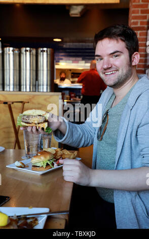 Ein Mann hält eine Jucy Lucy aka Juicy Lucy Cheeseburger, ein Minnesota Spezialität in einem Duluth restaurant.. USA Minnesota Duluth. Stockfoto