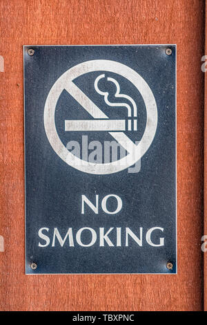 Nahaufnahme eines No Smoking Sign zu einem rötlich braunes Holz Unterlage verschraubt Stockfoto