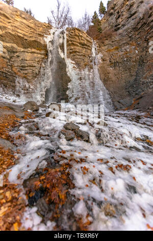 Gefrorenen Wasserfall auf einer robusten und erodierten Klippe mit Bäumen und Sky Overhead Stockfoto