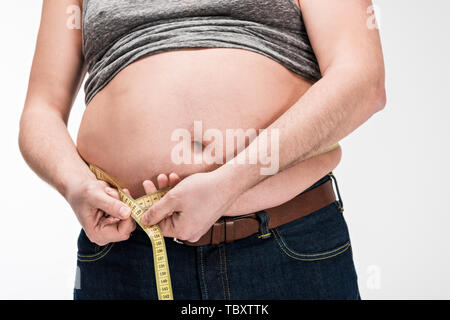7/8-Ansicht von übergewichtigen Menschen messen Taille mit Klebeband isoliert auf weißem Stockfoto