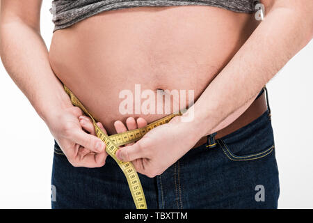 7/8-Ansicht von übergewichtigen Menschen messen Taille mit Klebeband isoliert auf weißem Stockfoto