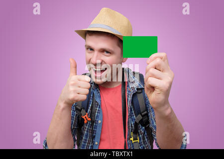 Junge attraktive touristische Mann hält grüne Kreditkarte. Stockfoto