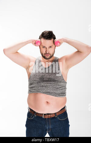 Übergewicht Mann an der Kamera schaut während der Arbeit aus mit rosa Hanteln isoliert auf weißem Stockfoto