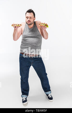 Übergewichtiger Mann in Tank Top holding Hot Dogs auf Weiß Stockfoto