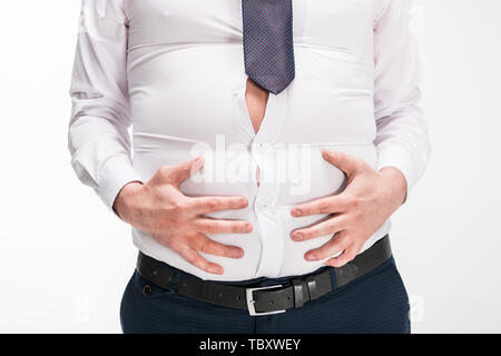 7/8-Ansicht von übergewichtigen Menschen in engen formalen Verschleiß Bauch berühren auf Weiß isoliert Stockfoto