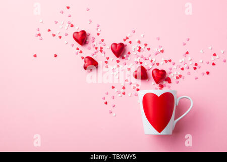 Becher mit Zucker und Schokolade Herzen auf rosa Hintergrund. Flach Komposition. Stockfoto