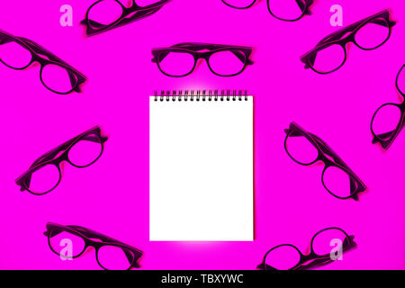 Notizblock mit trendigen Blau Brille auf rosa Hintergrund. Stockfoto