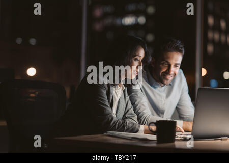 Lächelnd Geschäftsleute sitzen in einem Büro arbeiten overtme bei Nacht Stockfoto