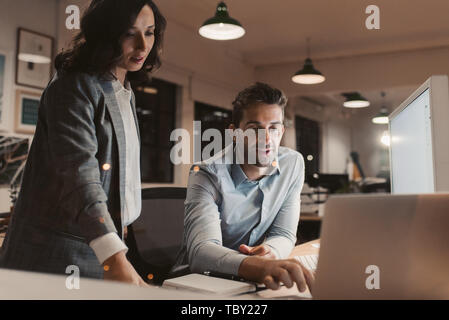 Zwei junge Geschäftsleute spät in einem Büro arbeiten zusammen Stockfoto