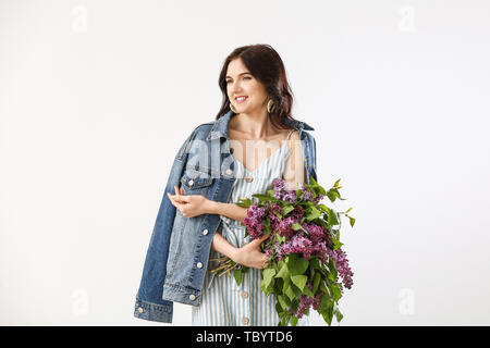 Schöne junge Frau mit Blumenstrauß aus lila Blumen auf weißem Hintergrund Stockfoto