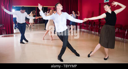 Junge lächelnde Menschen üben heftige jive Bewegungen im Tanz Klasse Stockfoto