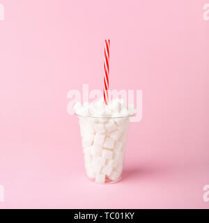 Schale aus Kunststoff mit Stroh voller Würfel Zucker auf Pastell rosa Hintergrund. Ungesunde Lebensmittel Konzept. Minimale, Vertikal, Seitenansicht. Stockfoto